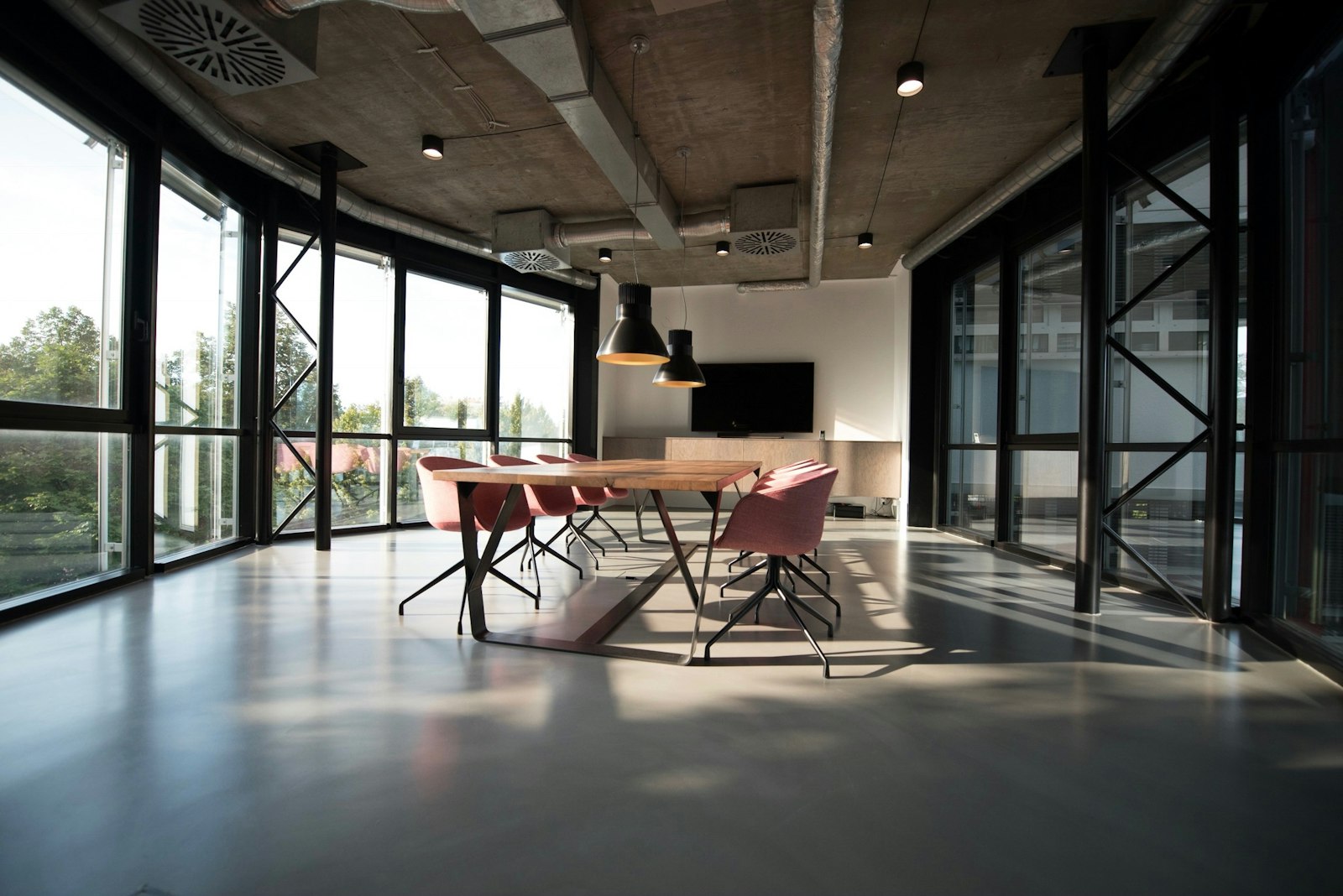 Boutique office interior with an exposed concrete ceiling, full-height glazing and a meeting table.