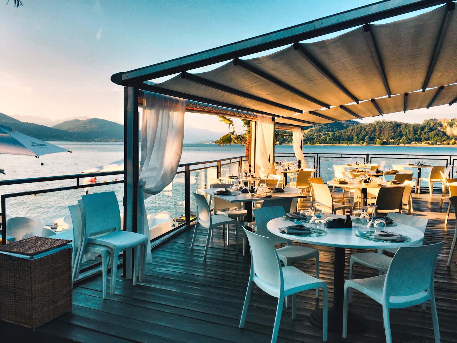 Waterfront terrace restaurant with pergola dining set at golden hour.