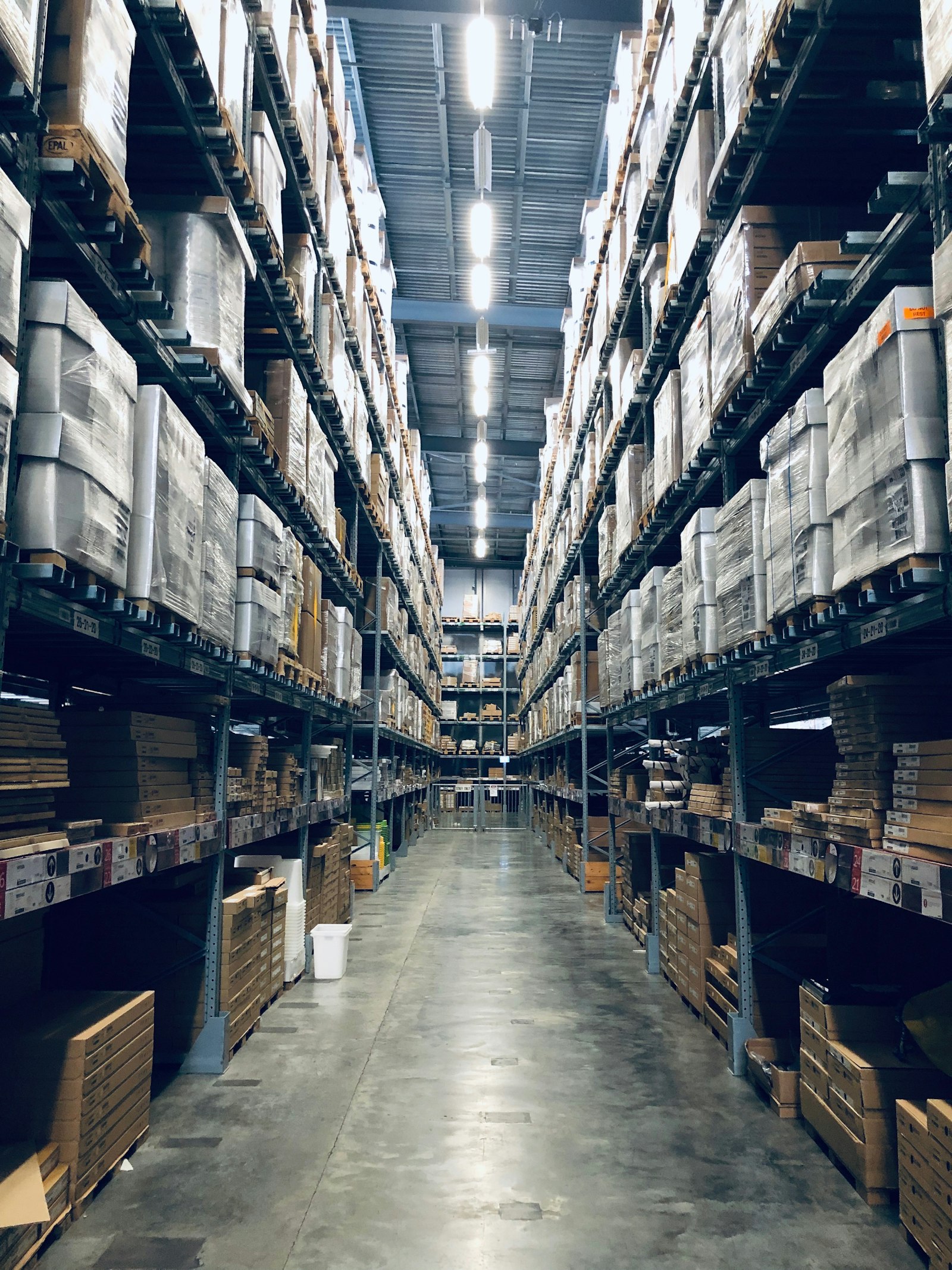Interior of a large modern warehouse facility with tall racking and a central aisle.